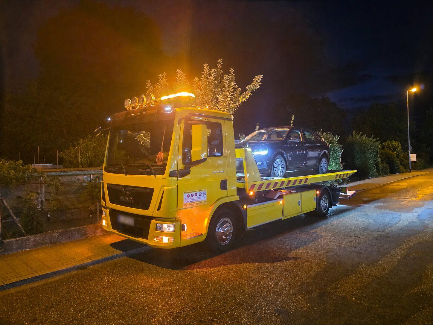 Gelbes ABS Abschleppfahrzeug mit verladenem Fahrzeug bei Nacht